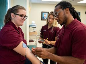 physical therapy student placing electrodes on arm